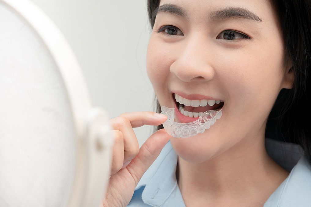woman putting in invisalign looking into mirror