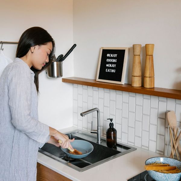 woman washing dishes with hot water