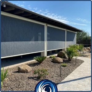 Exterior view of a long patio area enclosed with dark grey motorized retractable privacy screens, integrated seamlessly into the building's architecture. Exterior view of a long patio area enclosed with dark grey motorized retractable privacy screens, integrated seamlessly into the building's architecture.