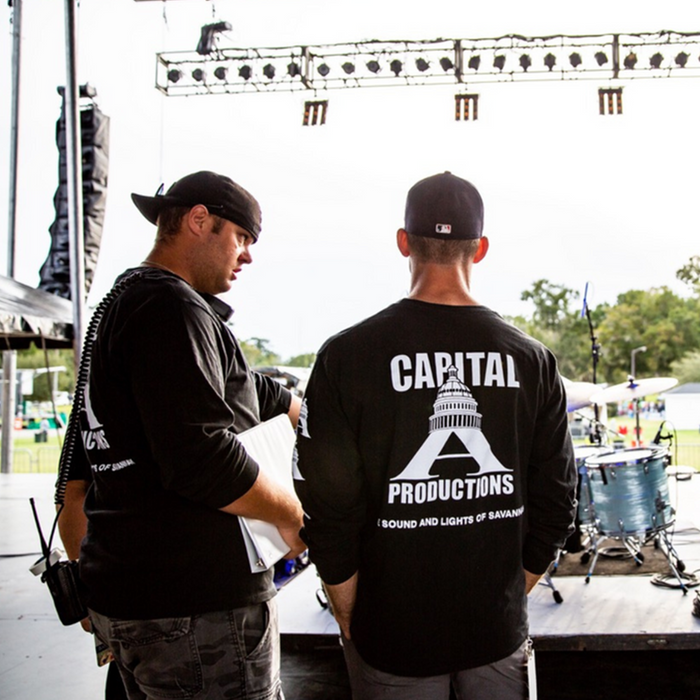Two Capital A crew members on a stage setting up