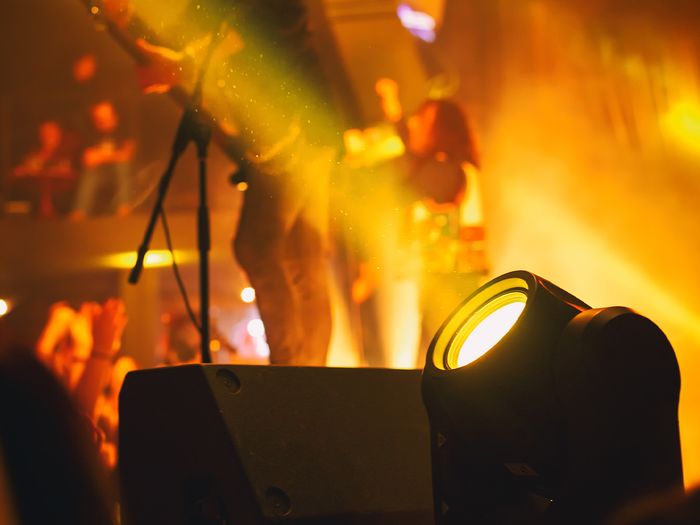 Spotlight shining offstage with a band in the background.