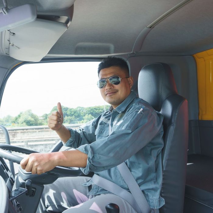 Happy moving truck driver giving thumbs up while driving