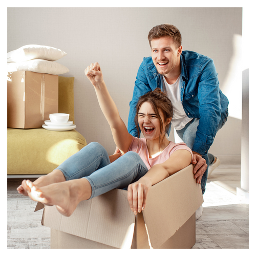 man pushing a woman sitting in a box while looking happy. 