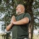 A middle-aged man practicing mindful meditation outdoors in a natural Virginia setting.