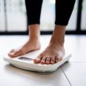 Close-up of a person’s feet on a modern scale, representing a medical weight loss journey.