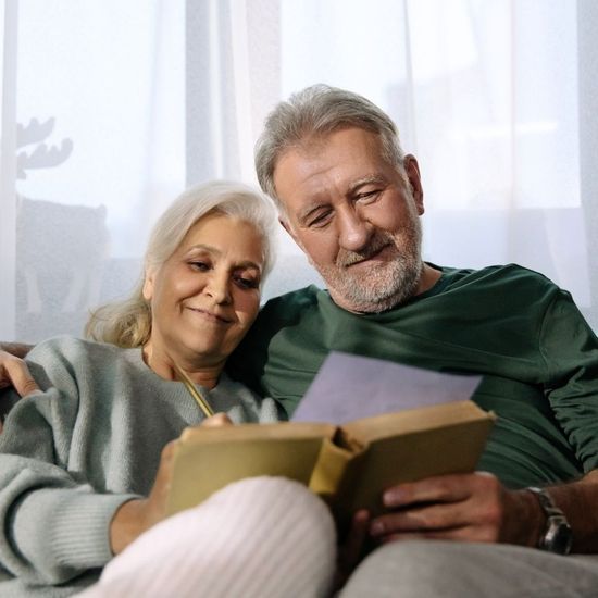 A happy middle-aged couple relaxing together on a sofa, illustrating the positive lifestyle outcomes of balanced hormone health.