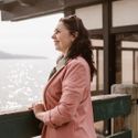 A smiling middle-aged woman in a pink blazer looking confidently into the distance.