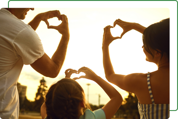 Family of three holding up a heart shape with fingers