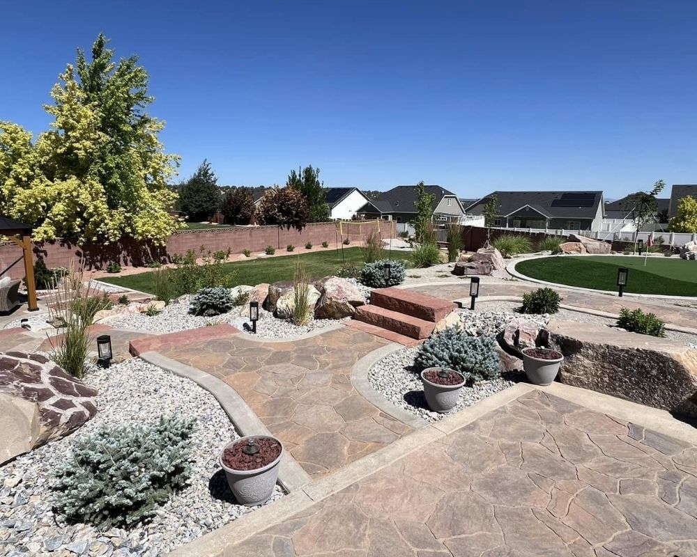 An expansive backyard terrace design featuring multiple levels of flagstone paving, stone planters, and a comprehensive irrigation system.