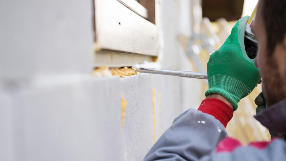 Man spraying insulation foam into a crack