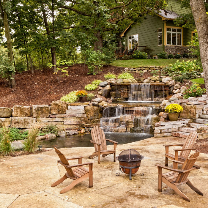 backyard with a waterfall, landscaping, and chairs