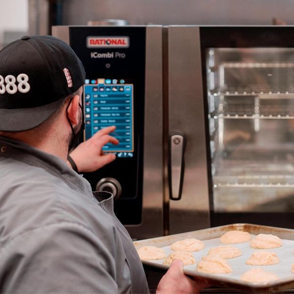 Man putting cookies in a high tech oven 