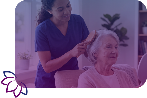 A compassionate caregiver gently brushes the hair of an elderly woman during a routine home care visit.