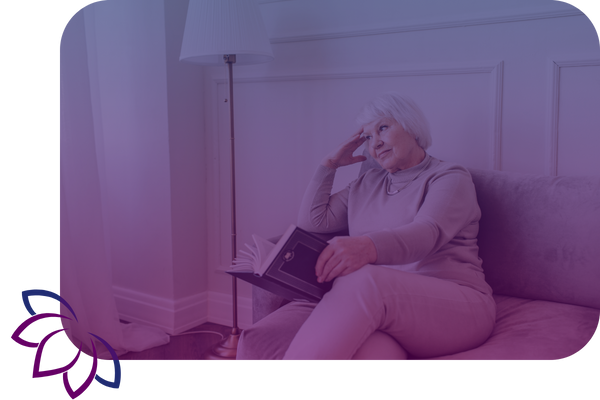 smiling older lady sitting on couch holding book