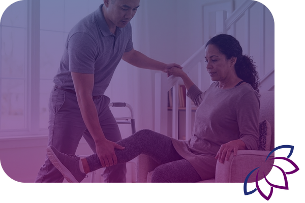 A physical therapist guides a woman through leg-strengthening exercises while she is seated in her home.