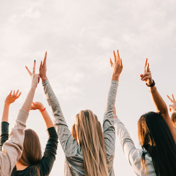 Group of  women with their hands in the air. 