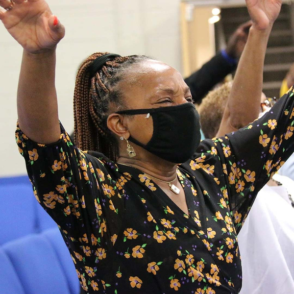 A woman from The Sanctuary at Kingdom Square Baptist church raises her hands in worship.