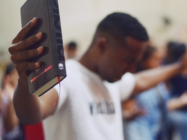 Man holding  up his bible in his hands during a worship service