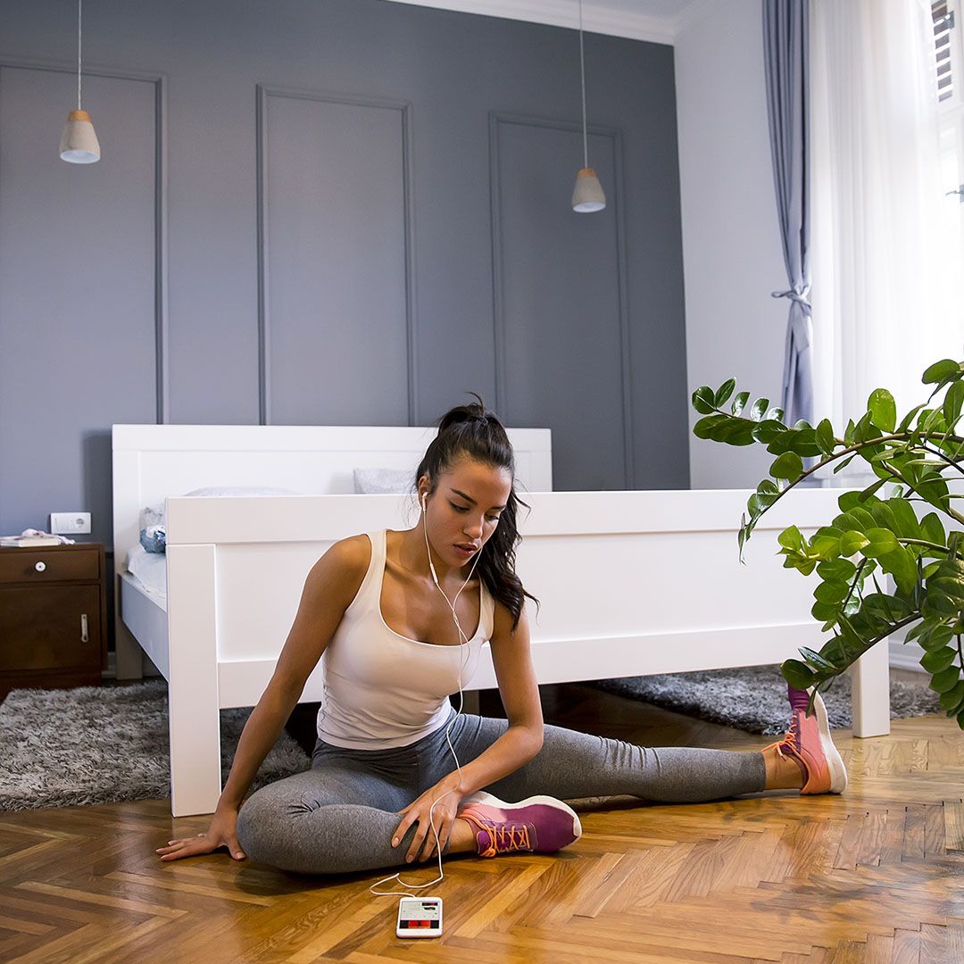  A woman stretching on the floor of her bedroom