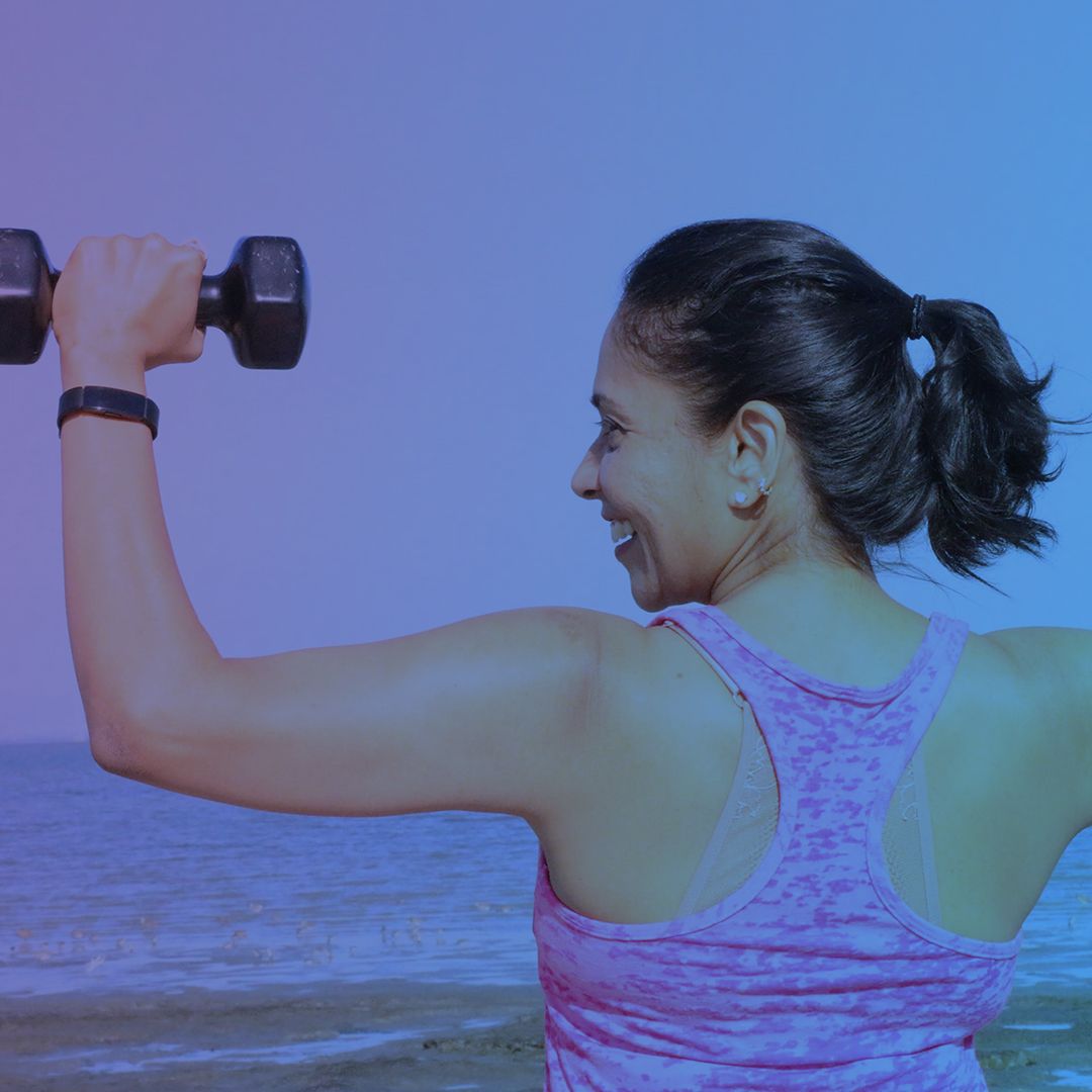 Woman lifting weights on the beach