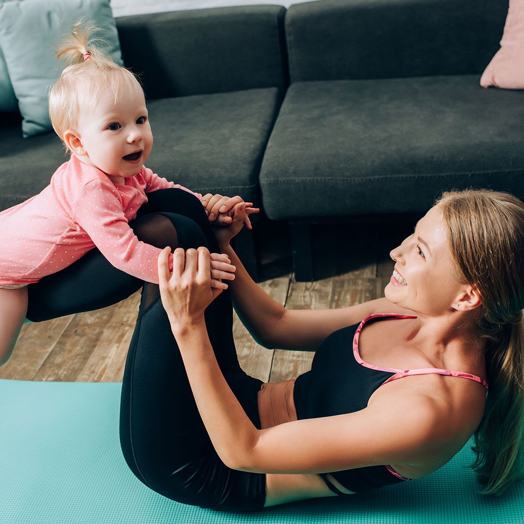 A woman doing crunches on the floor holding her baby.