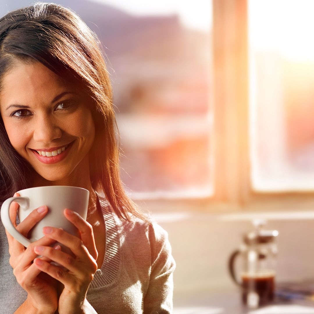  Indian woman with coffee at sunrise, smiling