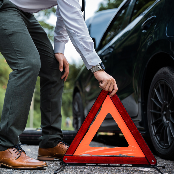 man putting a warning sign in front of his car. 