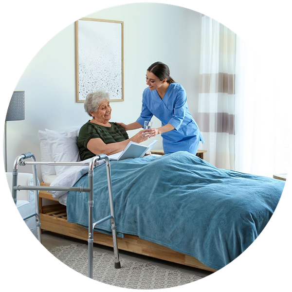 Nurse giving water to older woman in bed