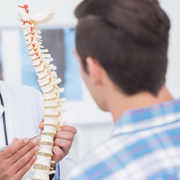 chiropractor showing man a model of a spine