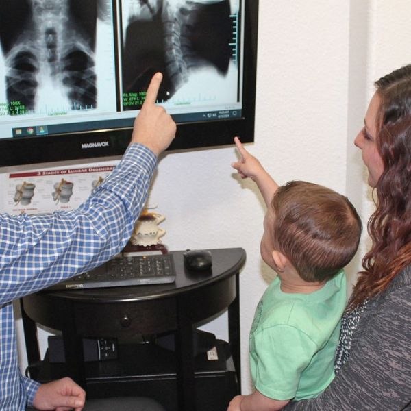 chiropractor going over x-ray with mom and toddler 
