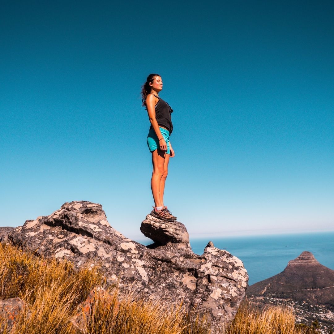 woman standing on top of mountain rock