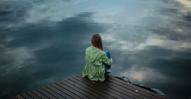woman sitting alone at the end of a dock