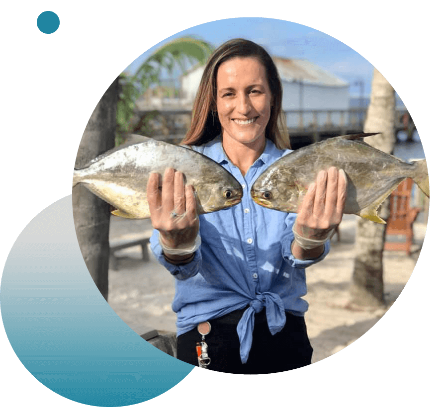 woman holding 2 fish on pier