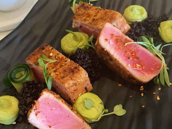 Tuna dish beautifully plated on black plate.