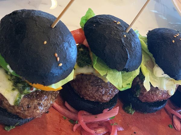 Fine dining burgers with black buns plated together.
