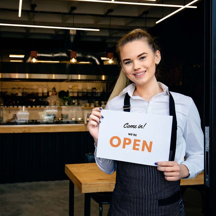 owner of a coffee shop holding an open sign