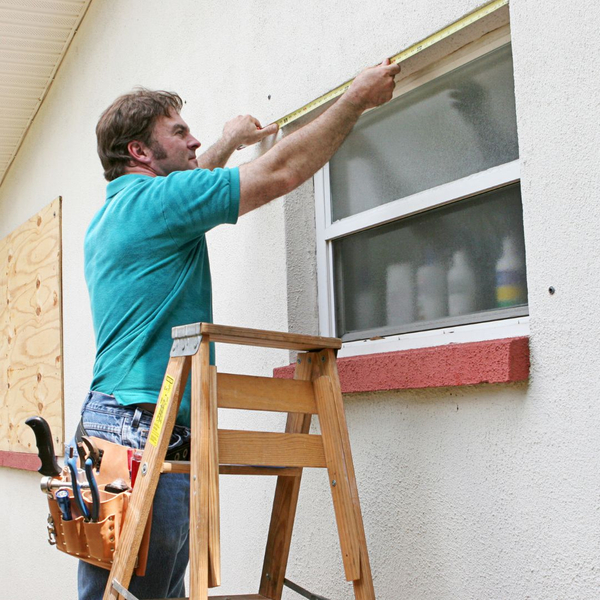 worker measuring a window frame