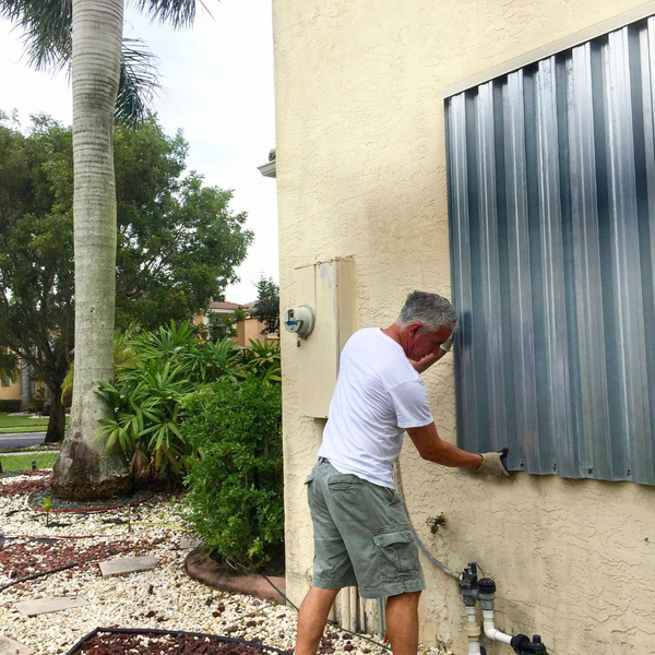 man installing metal hurricane shutters