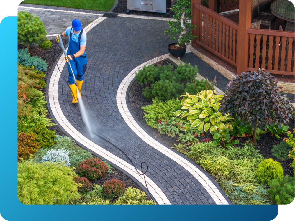 crew member pressure washing residential stone walkway