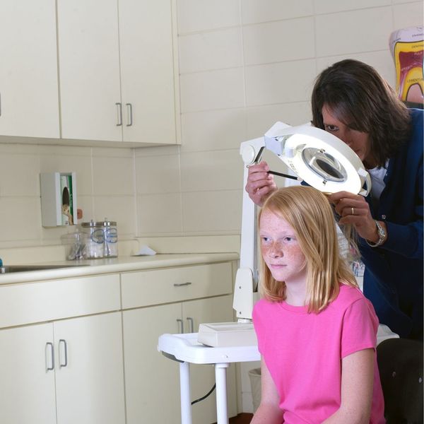 school nurse examining child's head for lice
