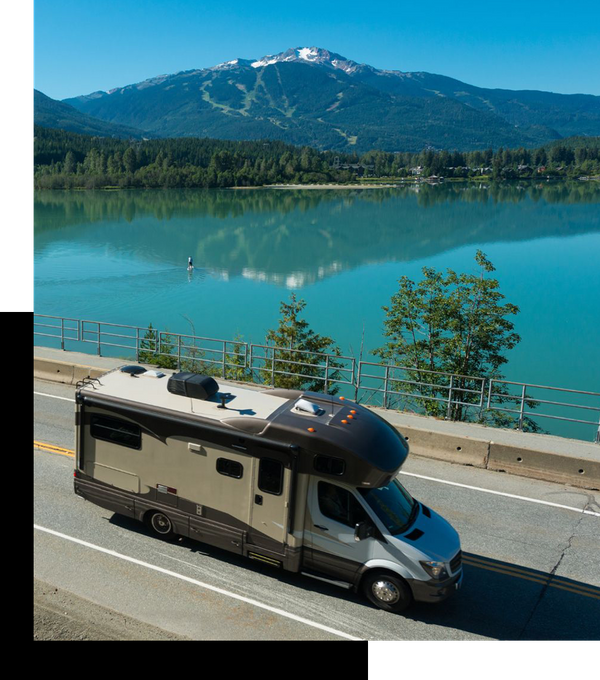 rv driving down a road next to a lake and mountain