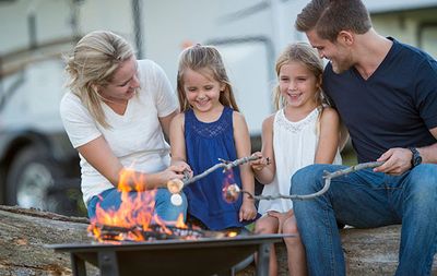 family roasting marshmellows in front of their rv
