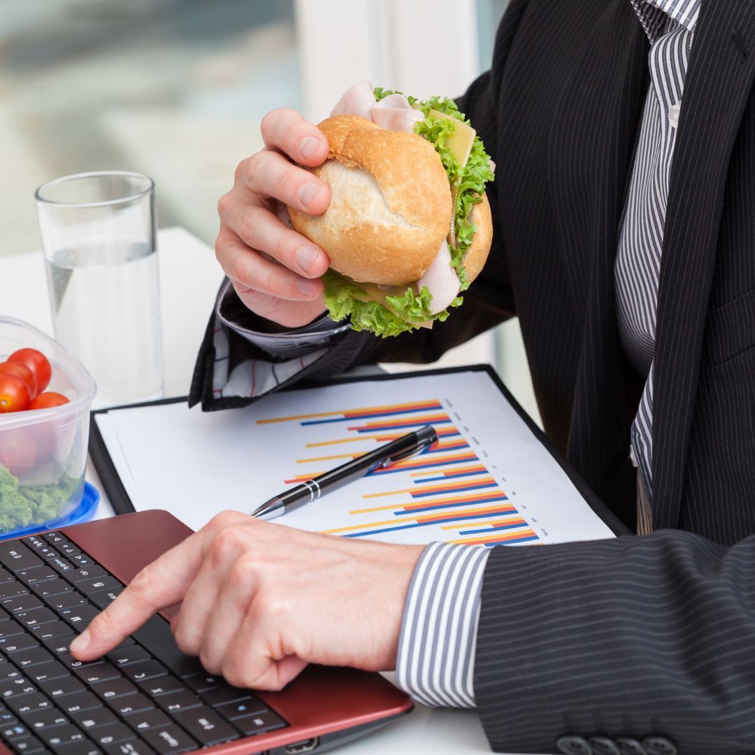 man eating sandwich while working on computer