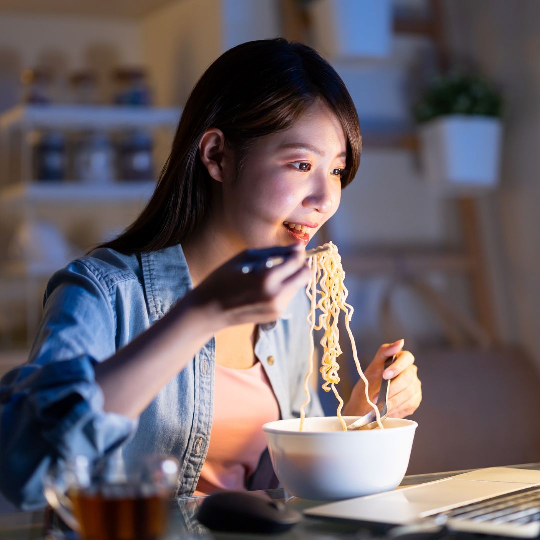 woman eating ramen at computer