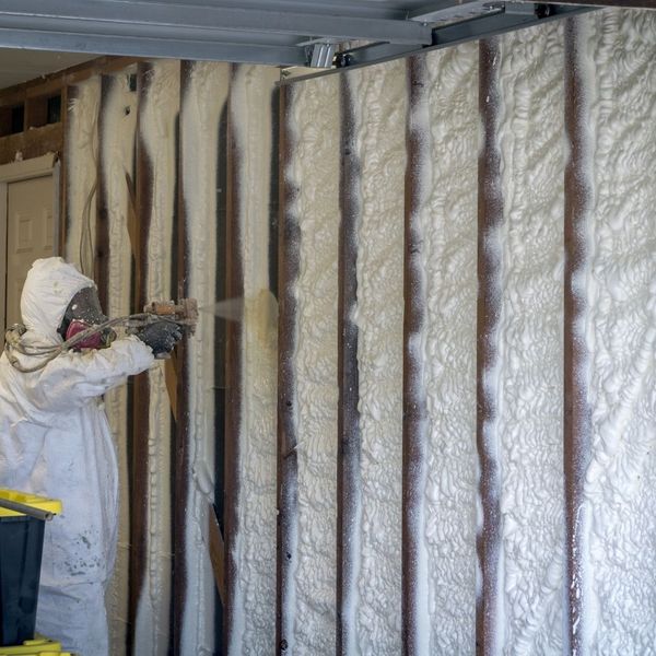 Person spraying foam insulation in a basement