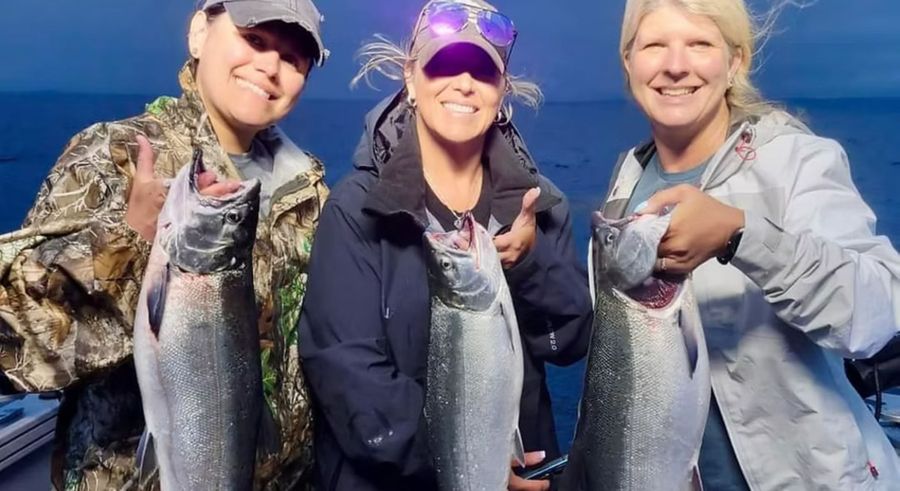 three woman at sunset posing with caught fish three woman at sunset posing with caught fish