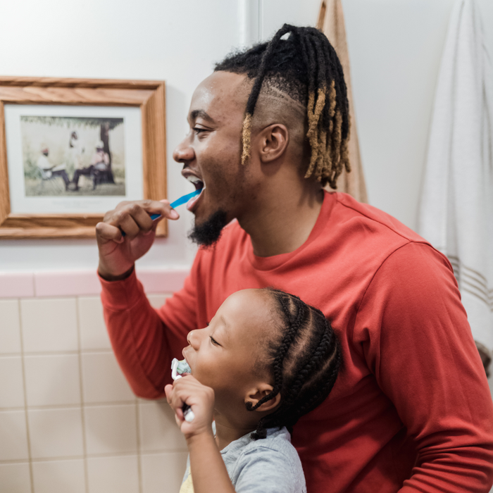 man brushing his teeth with son