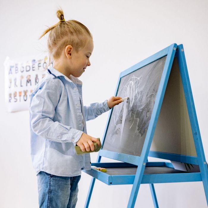a boy writing with chalk on a chalkboard