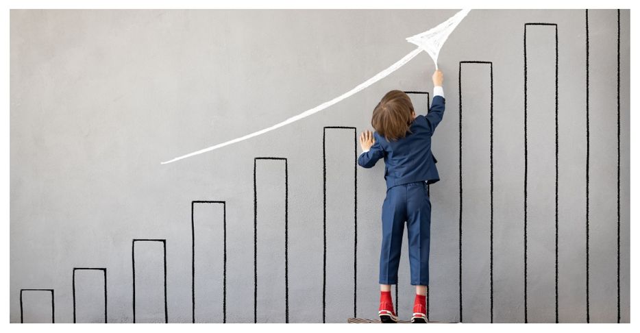 Child in suit drawing upward arrow on growth chart.