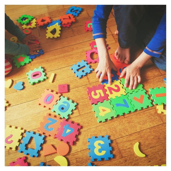 Children assembling colorful foam number puzzle pieces.